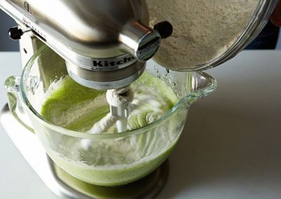 A green liquid is being mixed in a mixer for cooking with parsley.