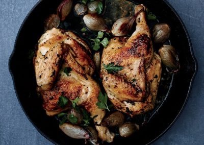 Roasted chicken with thyme and olives in a cast iron skillet, enhanced with mint.