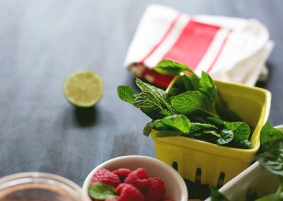 A bowl of raspberries and limes on a table.
