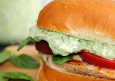 A chicken sandwich with a zesty green sauce made with cilantro on top.