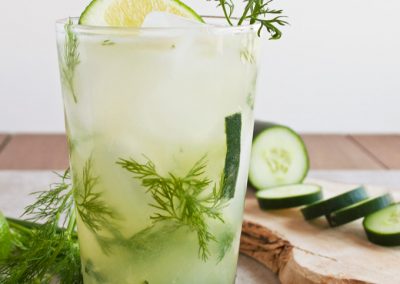 A refreshing drink with cucumbers and dill served on a wooden cutting board.