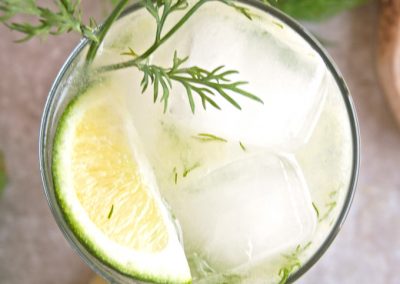 A tangy cocktail with lime and a savory touch of dill garnished with a slice of lime.