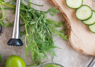 Cooking with Dill on a cutting board with cucumbers, lemons and limes.