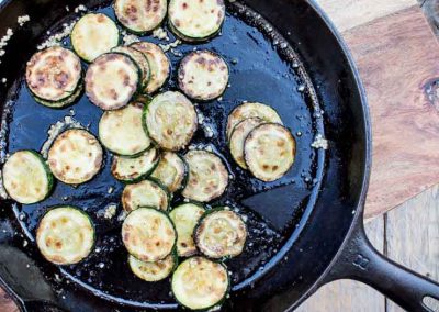 Fried zucchini with basil in a cast iron skillet.