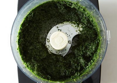 Cooking with green pesto in a food processor with parsley.